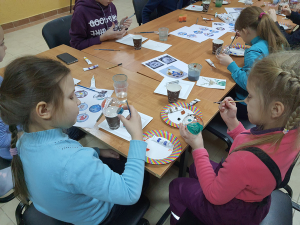 Две девочки рисуют красками за столом